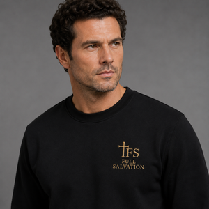 Man wearing the Full Salvation Apparel Essential Organic Cotton Crewneck Sweatshirt in Black, close-up of the embroidered gold cross emblem at the chest