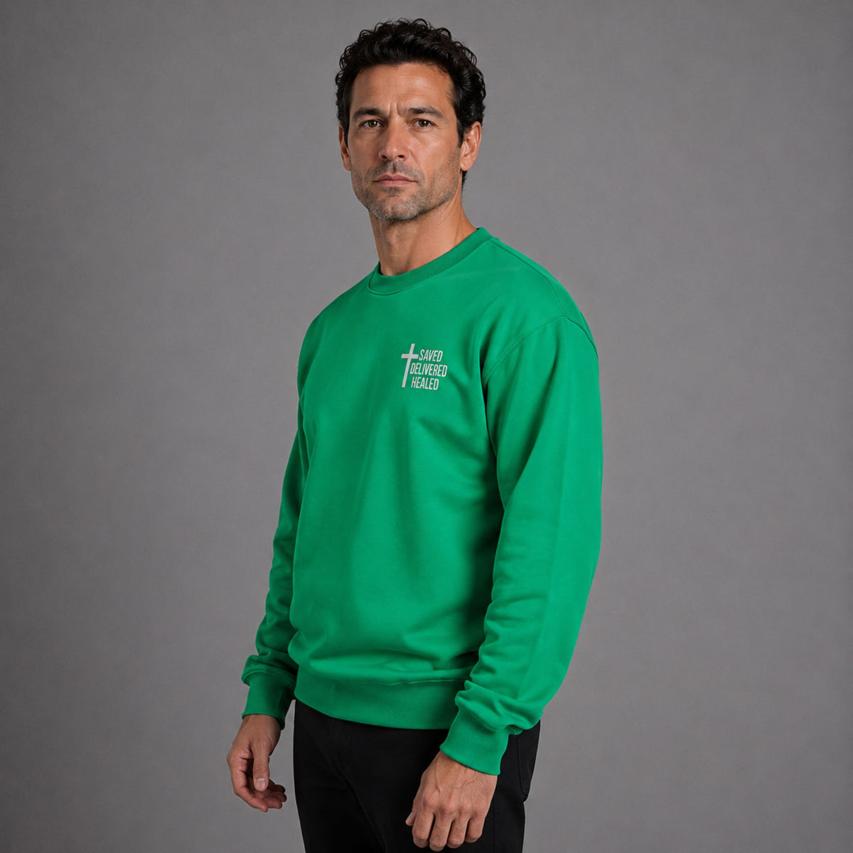Man wearing green Saved Delivered Healed embroidered crew neck sweatshirt