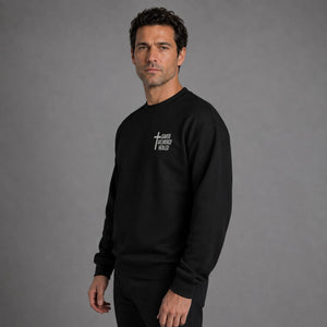 Man modeling black Saved Delivered Healed embroidered crew neck sweatshirt, three-quarter side view