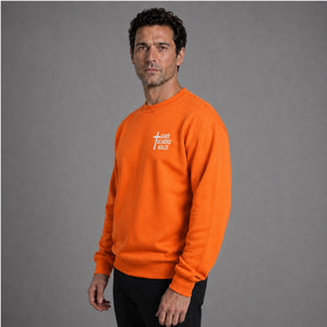 Man wearing orange Saved Delivered Healed embroidered crew neck sweatshirt